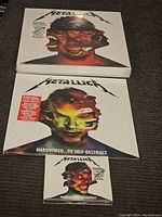 Photo of the three Metallica Hardwired...To Self-Destruct sets: cassette tape, 2 LP red vinyl, 2 CD set, all factory sealed showing cover artwork.