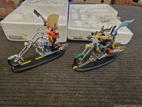 Two Looney Tunes figures of Yosemite Sam and Wile E. Coyote on motorcycles displayed with packaging foam in background.