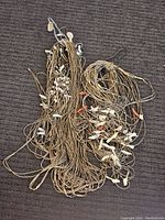 Multiple long, layered Southwestern necklaces with golden beads and bone or shell fetish carvings laid out on a dark fabric surface.