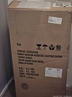 Photo of the large shipping box showing brand, model, color, and series details for the Randy Jackson acoustic-electric guitar.