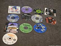 All 10 Sega Dreamcast game discs arranged on carpet, showing various titles including Sonic Adventure, Tony Hawk's Pro Skater, NFL 2K1, Sega Sports and others.