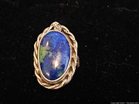 Front view of the sterling silver ring showing an oval cabochon blue-green stone with detailed silver bezel.