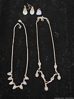 Lot showing all items: two necklaces with multiple moonstone pendants and two pairs of moonstone earrings on black background
