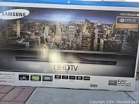 Full front of shipping box showing Samsung UHDTV branding and cityscape graphic
