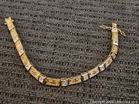 Full length of sterling silver tennis bracelet displayed on dark woven fabric background.