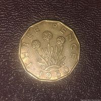 Reverse of the 1950 UK three pence coin showing thrift flowers and denomination date.