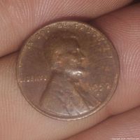 Obverse side of the 1957 Lincoln cent coin showing Abraham Lincoln's profile, year '1957', and inscriptions including 'IN GOD WE TRUST' and 'LIBERTY'. The coin shows signs of wear and tarnish.
