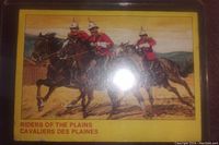 Front of the card showing three mounted RCMP members in red serge uniforms with spiked helmets, labeled Riders of the Plains.