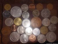 Image showing a variety of older coins from Canada, USA, UK, and other countries with mixed condition and metal types arranged flat on a dark surface.