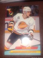 Hockey card showing Pavel Bure in Vancouver Canucks uniform on ice, holding hockey stick, with card branding in top left corner and player info at bottom.