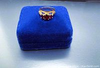 Front view showing the 3 oval garnet stones set in 10K yellow gold with filigree leaf patterns on the sides.