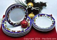 Four stacked dinner plates, four stacked dessert plates, and four stacked soup bowls, all with Santa and sleigh motif on blue rim, holiday decor in background