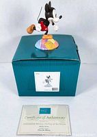 Millennium Mickey figurine posed on top of its original box with certificate of authenticity in front.