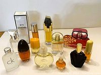Photo showing assortment of eleven eau de parfum bottles with varied sizes and shapes including boxed Chanel No 5 and recognizable brands Calvin Klein, Elizabeth Taylor, Givenchy, Chloe, Coty, Clinique.