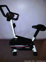 Side view of Healthware 354 exercise bike showing black and white frame, padded seat, and digital monitor on handlebar.