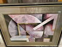 Framed abstract geometric print with textured metallic effect and gold foil highlights, gold tone mat, black and gold wooden frame.