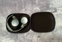 Black Philips PH805 wireless over-ear headphones inside the open hard zippered carrying case, placed on a grey fabric surface.