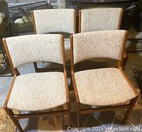 Front view of four teak dining chairs grouped together