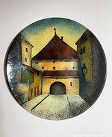 Front view of the round hand-painted enamel plate, showing the street scene of Kamenita Vrata in sunset hues, measuring 12 inches diameter.