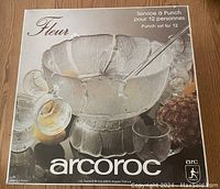 Original boxed packaging photo showing the stamped Arcoroc France brand and Fleur flower petal punch bowl set designed for 12 people, including bowl, cups, and ladle