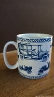 Porcelain mug showing detailed blue vintage motor car illustrations and geometric borders