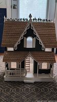Full view of Victorian model doll house showing front porch, roof with scalloped shingles, and ornamental trim