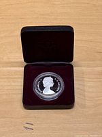1987 proof Canadian silver dollar in protective capsule inside black velvet-lined display case.