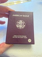 Outer cardboard box in maroon with embossed text and Presidential Seal logo.
