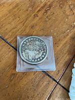 Obverse side of silver coin showing Liberty with flowing hair surrounded by stars, in protective case.