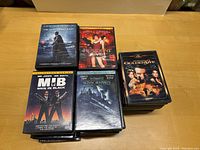 Top view of several DVD cases including The Dark Knight Rises, Resident Evil, Men in Black, Edward Scissorhands, and GoldenEye stacked on table.