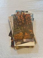 Stack of vintage postcards featuring various nature scenes including a prominent autumn tree with orange foliage on top