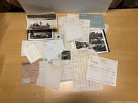 Overview of papers, receipts, letters, and photographs spread out on a table, mostly typed and handwritten documents of various sizes on aged paper.