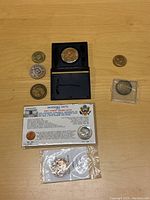 Top view of miscellaneous coins and tokens including in packaging and holders on wood surface.