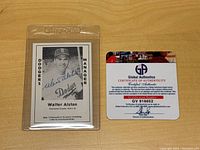 Front and back view of the autographed 1979 Donruss Legends Walter Alston baseball card in protective Ultra PRO case alongside the Certificate of Authenticity from Global Authentics.