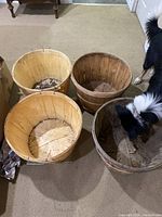 Four round wooden baskets on carpet, one with darker wood tone and three lighter, viewed from above at an angle, dog partially visible.