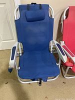 Blue beach chair with padded headrest, white frame, and blue armrest padding