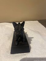 Front view of black cast iron Scottie dog doorstop on rectangular base.
