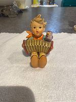 Front view of Hummel boy figurine playing accordion with bird perched
