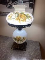 Full view of vintage hurricane lamp with floral pattern and decorative base