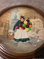 Plate with elderly woman balloon seller in front of The London Pavilion, framed in wood