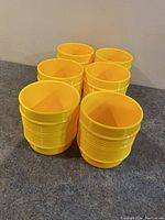 Six yellow vintage Rubbermaid stackable cups shown arranged in two rows on a countertop, highlighting their color and shape.
