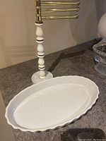 White ceramic oval serving platter placed on countertop under brass and white stand