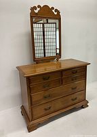 Full view of wooden dresser with attached decorative mirror and six drawers.