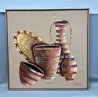 Frontal view of the impasto oil painting showing pottery vessels and a woven basket with geometric designs on beige background, framed.
