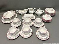 Full set of Johnson Bros china pieces including cups, saucers, plates, bowls, butter dish, sugar bowl, creamer, and gravy boat with visible floral pattern and red trim.