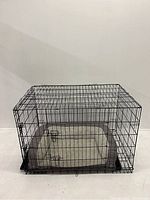 Front view of large black metal dog kennel with latch and mattress.
