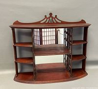 Front view of vintage wooden wall shelf with mirrored panels and decorative carved top