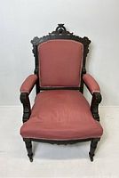 Front view of Victorian Eastlake armchair highlighting carved crest and pink upholstered cushion and arms.