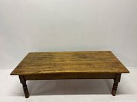 Front view of the vintage pine top center table showing the wood grain and turned legs