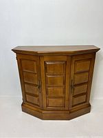 Front view of vintage wooden corner cupboard with three paneled doors and metal handles.